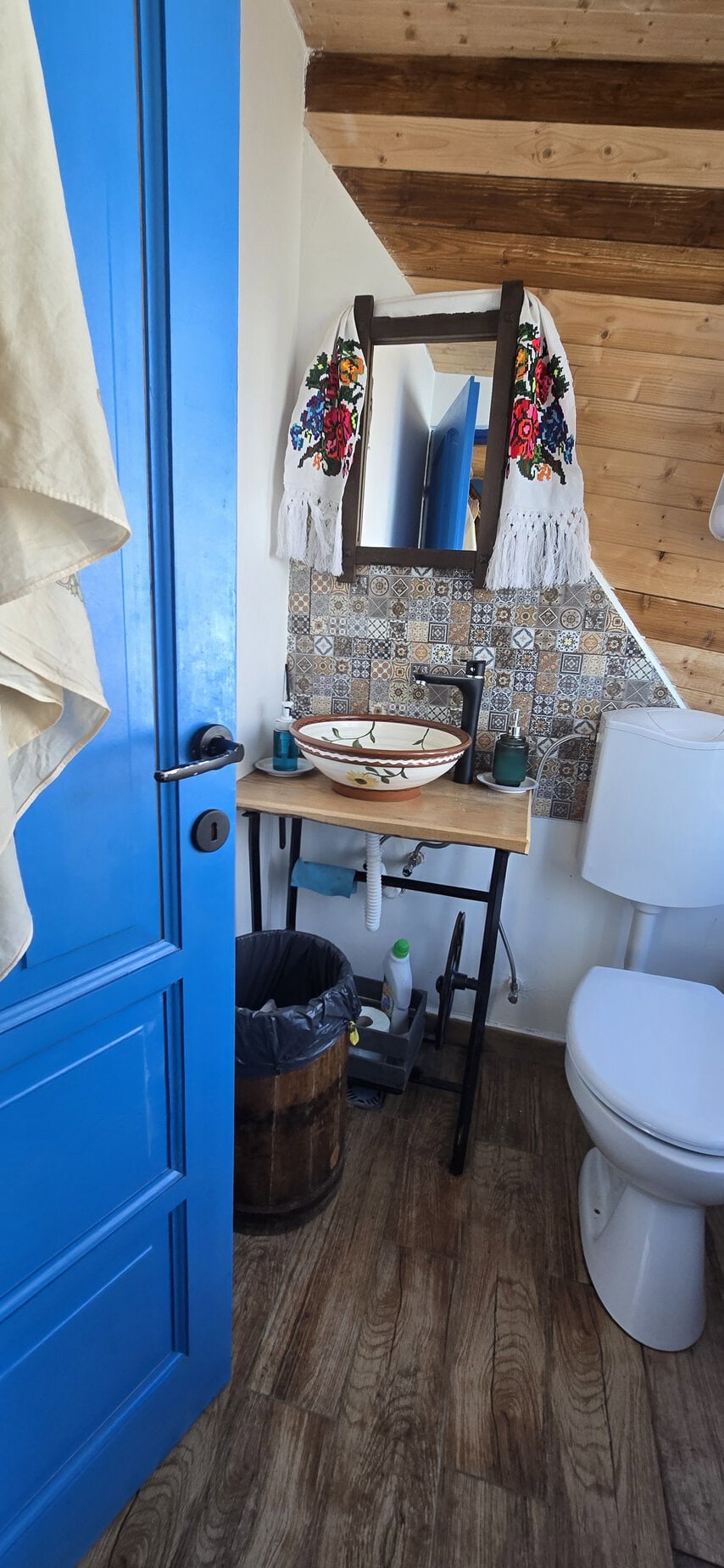 Oglindă decorativă cu perdele brodate, în baie rustică.