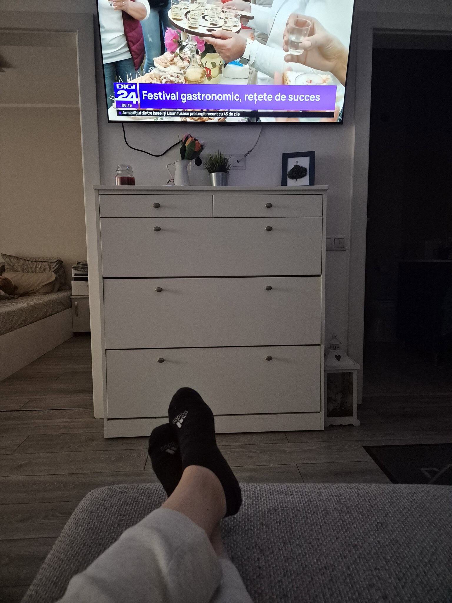 O alt tag: Persoana relaxându-se pe canapea, privind televizorul în living.