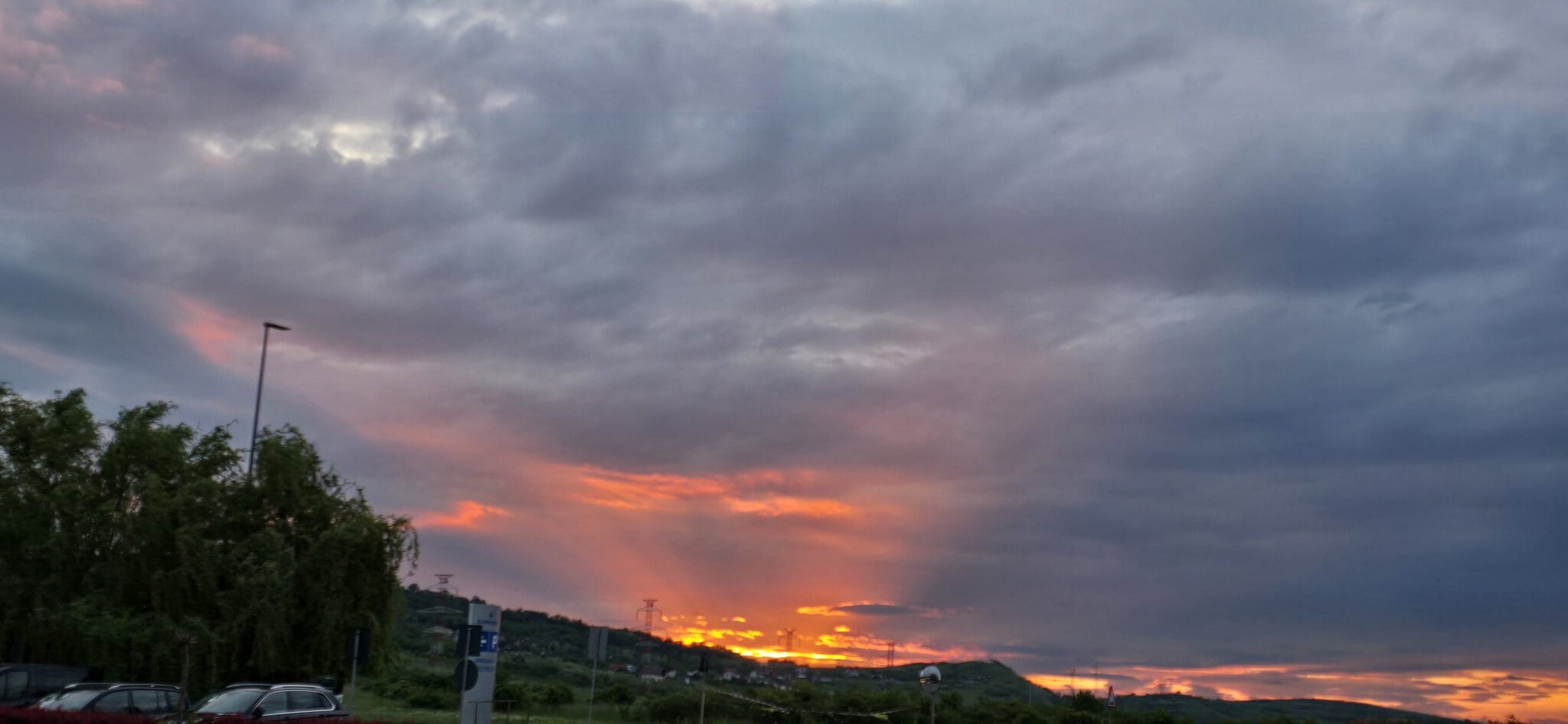 Vedere de apus de soare cu cer înnorat și lumini calde pe orizont.