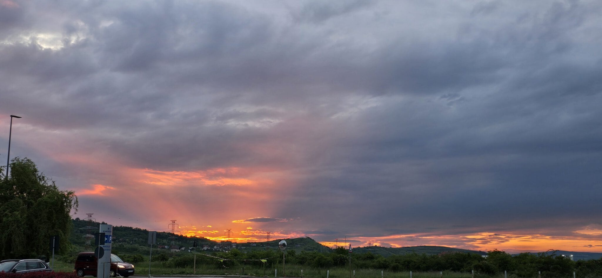 Vedere de apus de soare cu cer înnorat și peisaj rural.