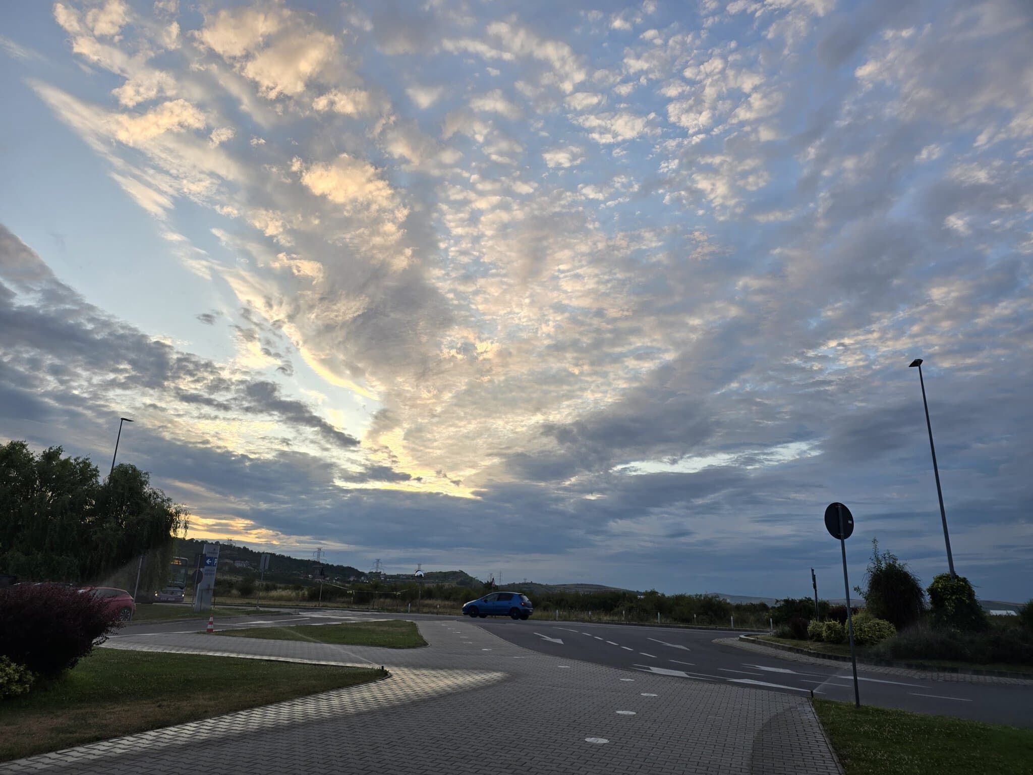 Cer dramatic la apus cu nori altocumulus iluminați în nuanțe de auriu și albastru deasupra unui sens giratoriu